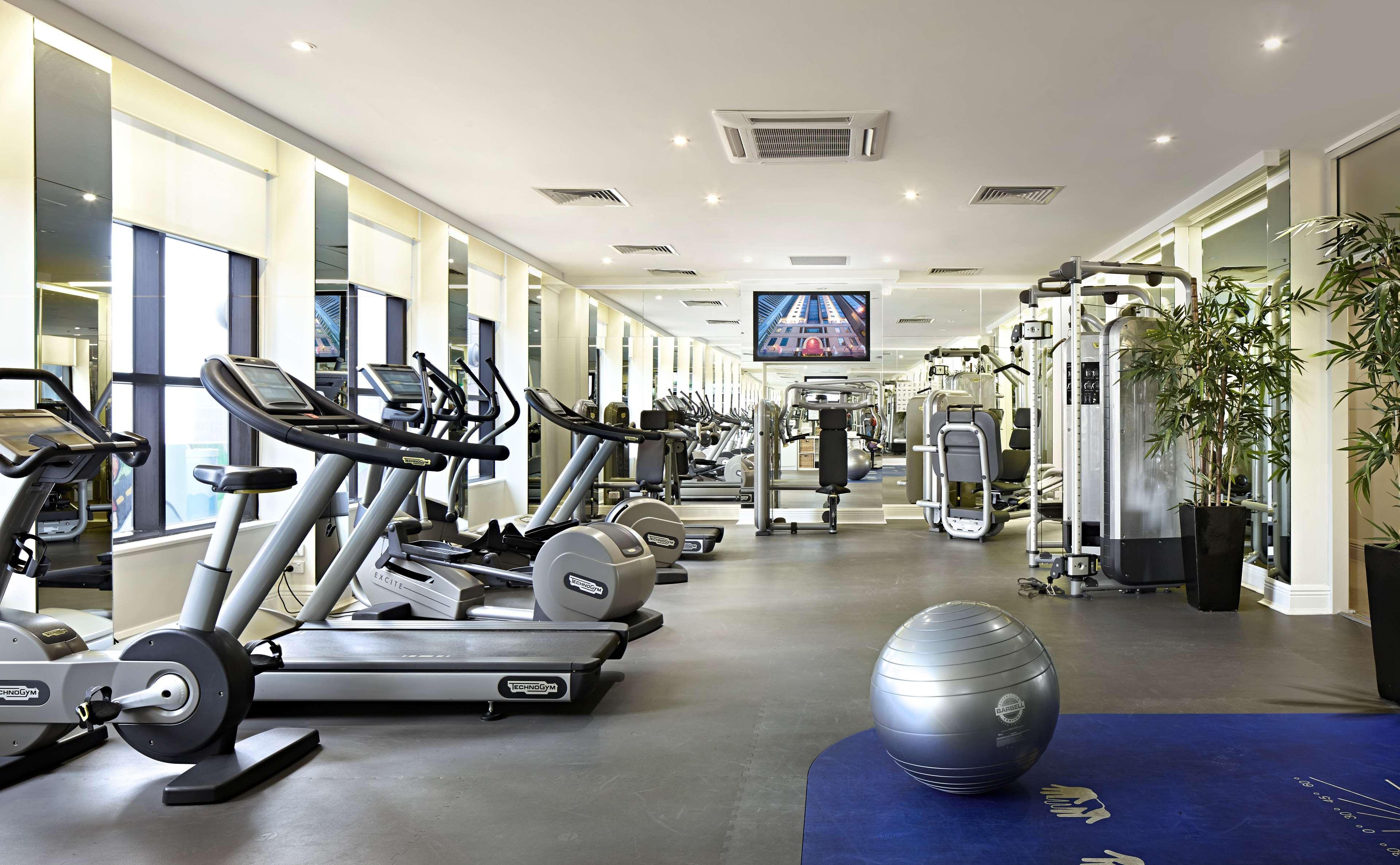 Hotel Stamford Plaza Melburne Exterior foto The photo shows a modern gym or fitness center. There are several exercise machines, including treadmills and elliptical trainers, positioned near large windows that allow natural light to flood the space. A television is mounted on the wall, likely 