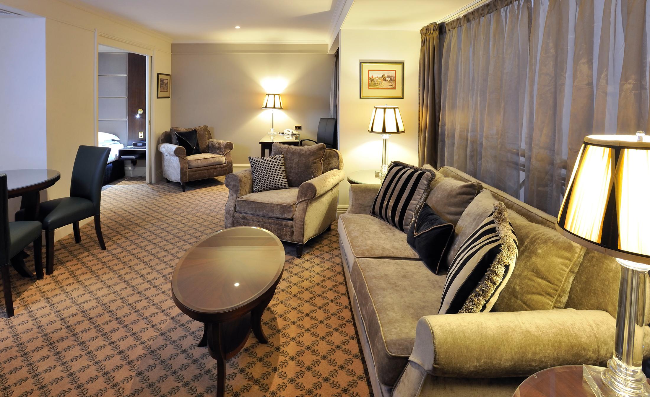 Hotel Stamford Plaza Melburne Exterior foto The photo shows a stylish and comfortable living area. It features plush seating, including a sofa with decorative cushions and a couple of armchairs. There's a circular coffee table in the center of the seating arrangement. The room has soft lightin