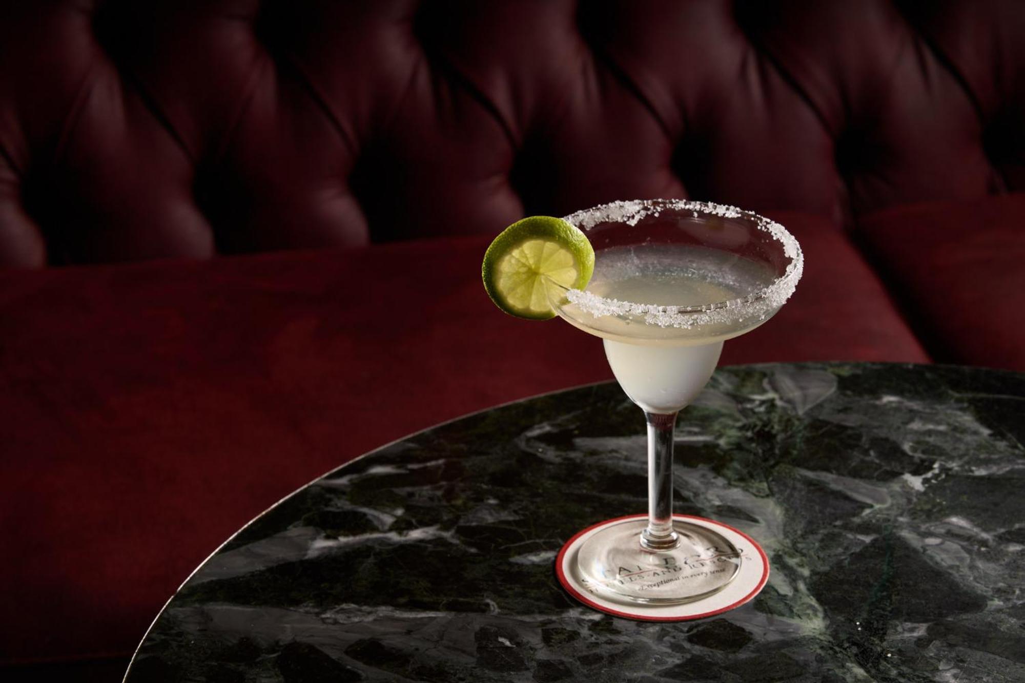 Hotel Stamford Plaza Melburne Exterior foto The photo shows a beautifully presented margarita cocktail served in a classic margarita glass. The drink is clear with a salt rim around the edge, and adorned with a slice of lime. The glass is placed on a dark green marble table, contrasting with a