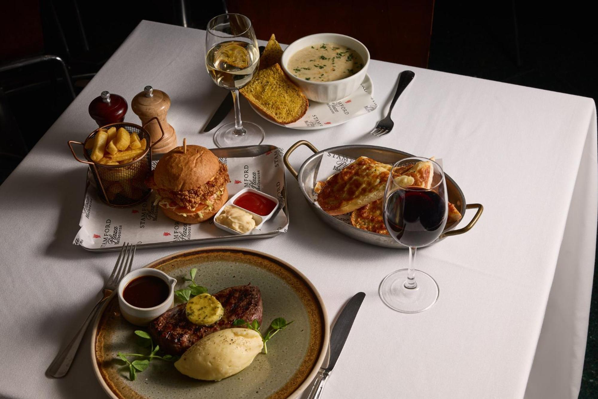 Hotel Stamford Plaza Melburne Exterior foto The photo showcases a variety of food and drinks arranged on a table set with a white tablecloth. 

1. **Main Dish:** A plate features a portion of steak topped with a slice of butter, accompanied by mashed potatoes and a garnish of greenery.
2. **Bu