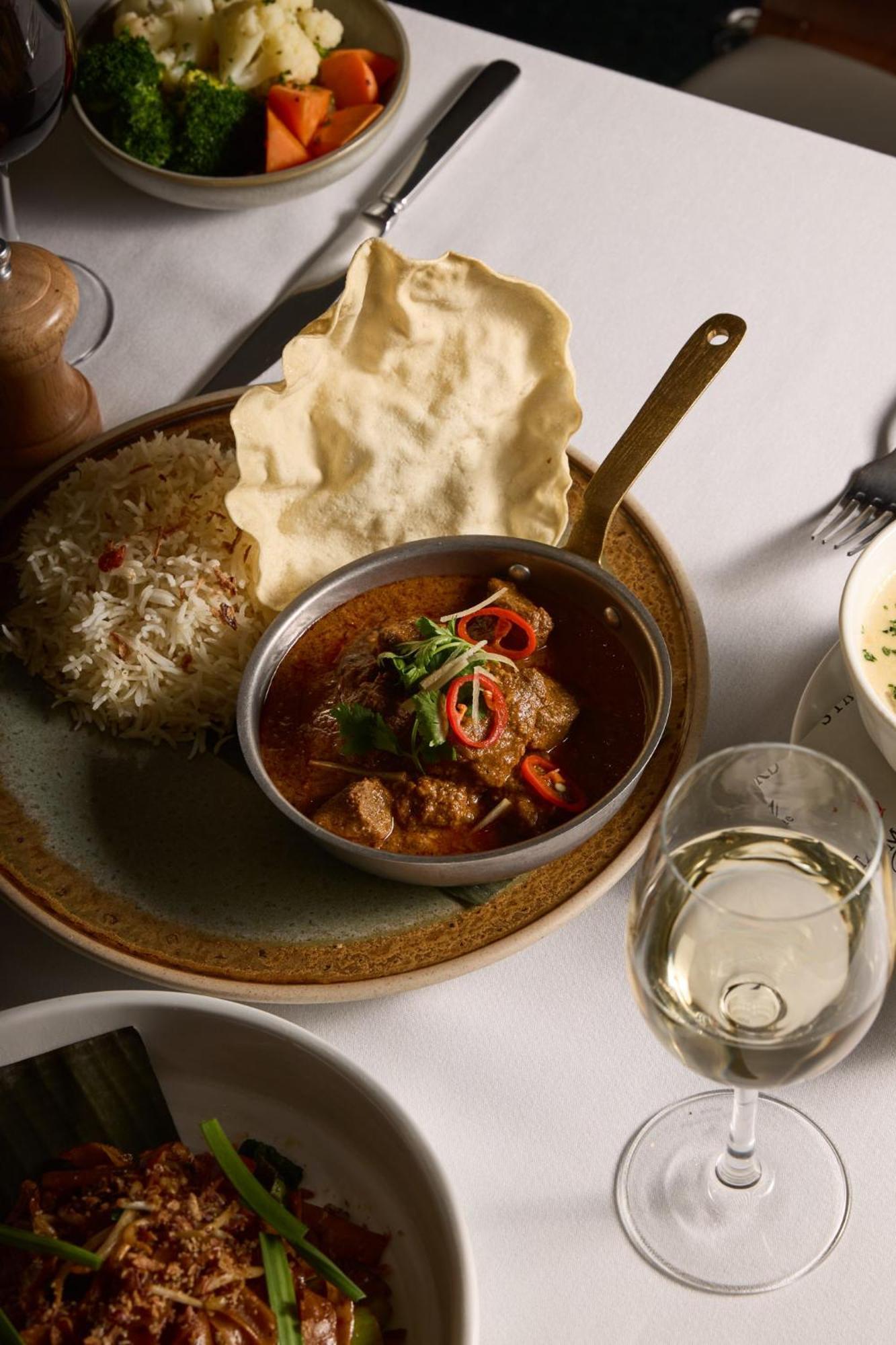 Hotel Stamford Plaza Melburne Exterior foto The photo features a plated meal that includes a serving of meat curry in a small round dish. The curry is garnished with herbs and slices of chili. Accompanying the curry, there is a mound of fluffy rice, and a piece of crispy flatbread (poppadom) r