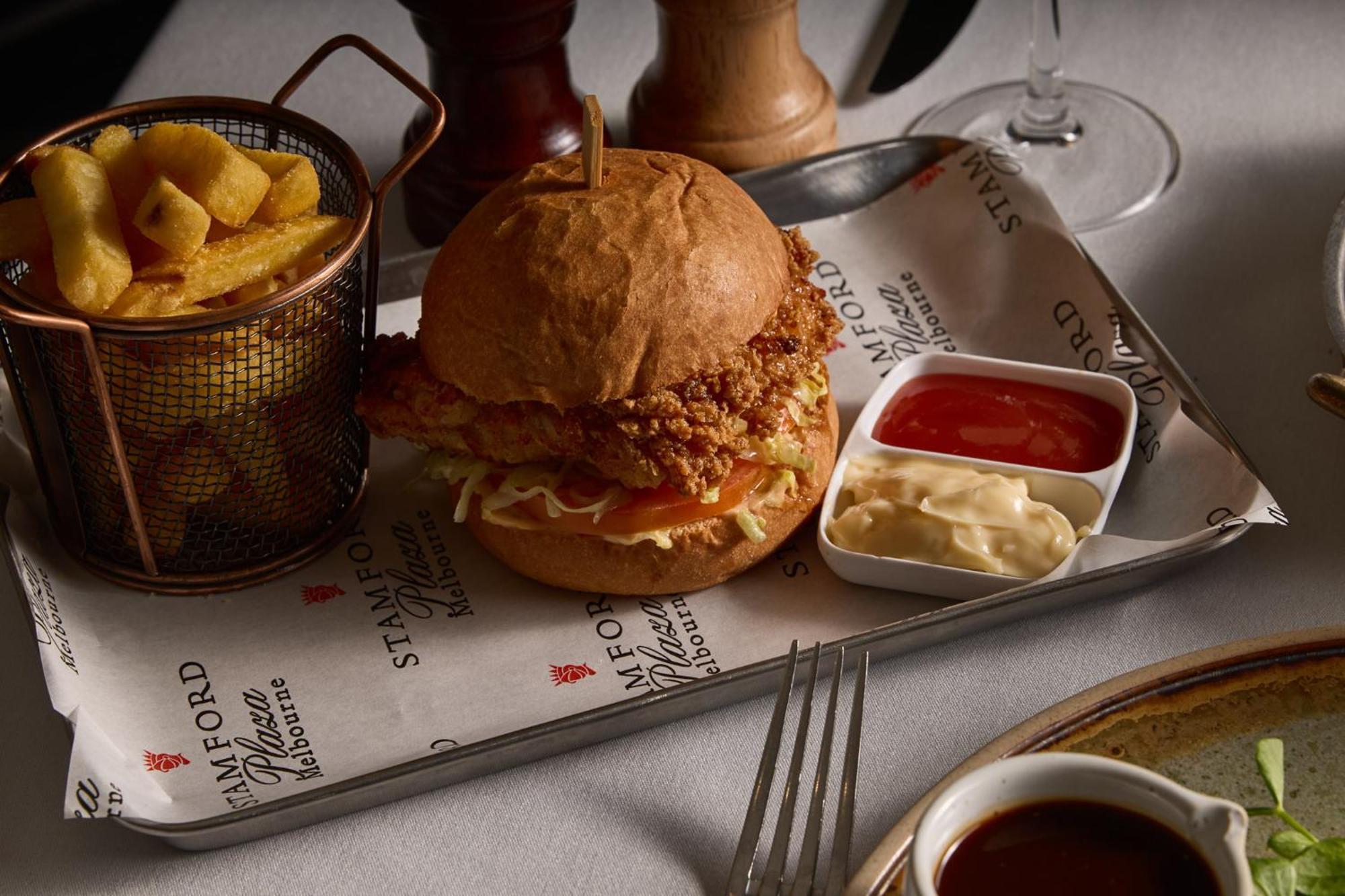 Hotel Stamford Plaza Melburne Exterior foto The photo features a meal served on a tray. In the center is a sandwich made with a golden-brown chicken fillet that appears crispy, placed inside a soft bun. The sandwich is likely complemented by some type of sauce or condiments underneath the chic