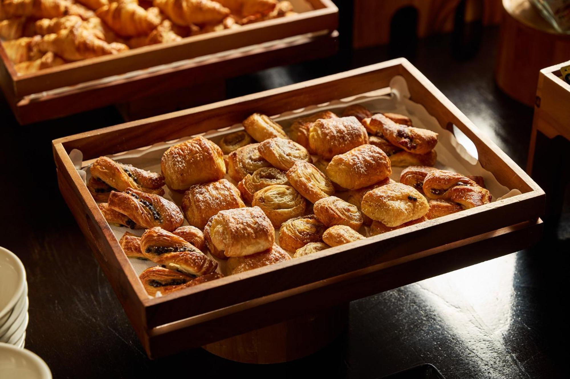 Hotel Stamford Plaza Melburne Exterior foto The photo shows a wooden tray filled with an assortment of baked goods. There are various types of pastries, including small, flaky items that appear to be puff pastries, and possibly some filled with chocolate or fruit. The pastries are golden brown