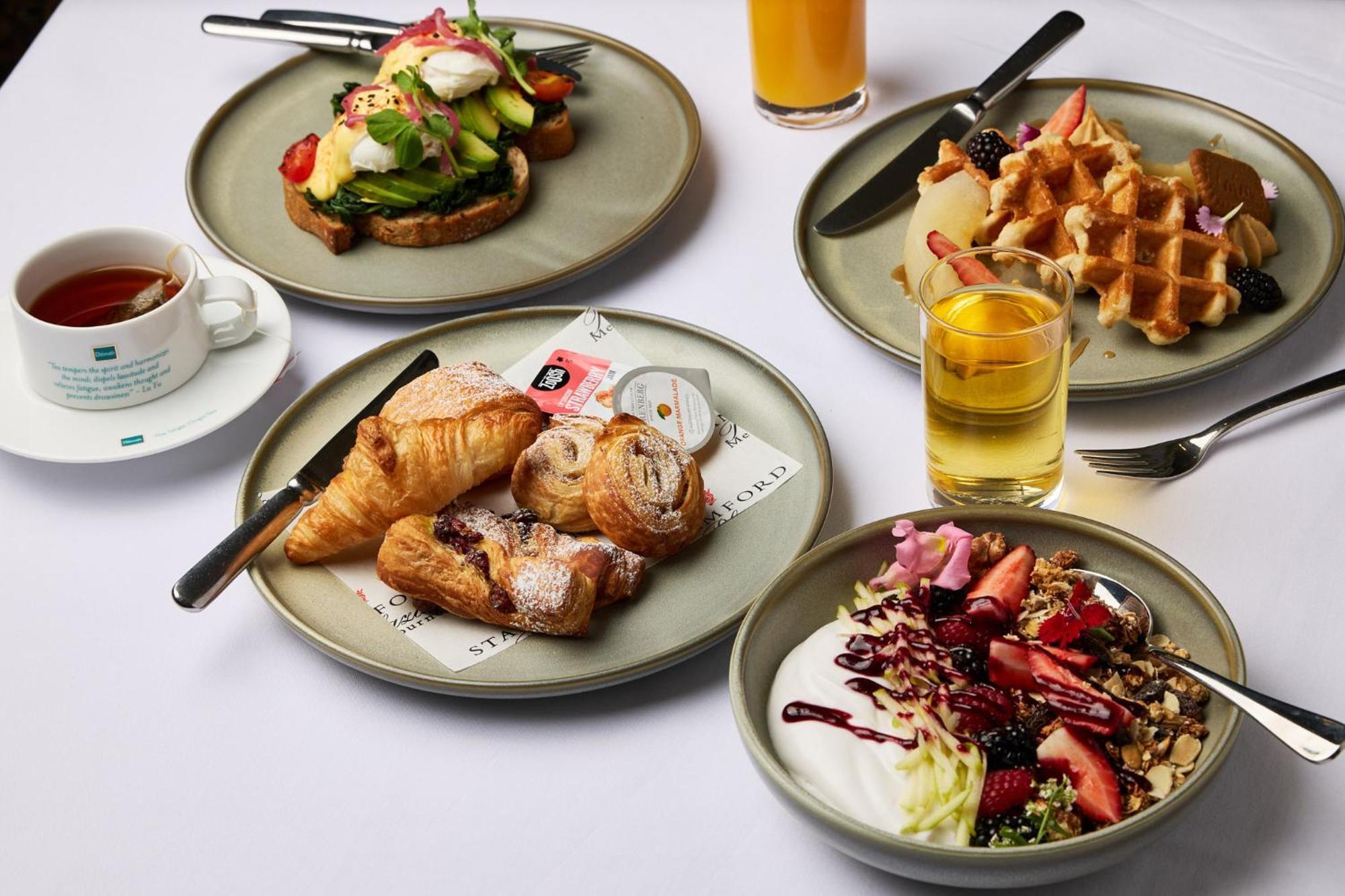 Hotel Stamford Plaza Melburne Exterior foto The photo displays a variety of breakfast items arranged on several plates. 

1. **Top-left Plate**: Features an open-faced sandwich with avocado, topped with poached eggs and garnished with vegetables.
2. **Top-right Plate**: Contains freshly made w