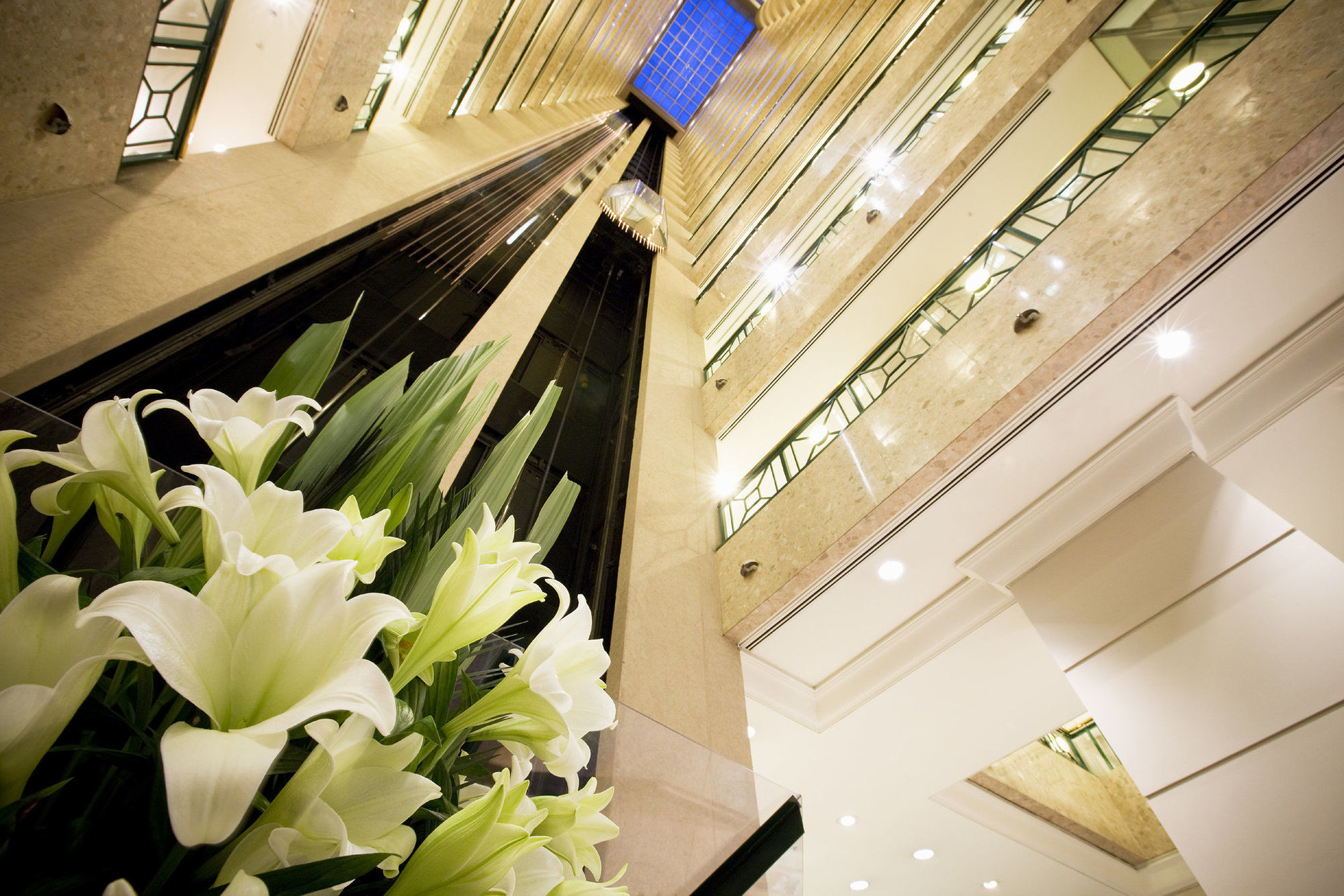 Hotel Stamford Plaza Melburne Interior foto The photo shows a modern indoor space, likely a lobby or atrium of a building. The view is looking upwards, capturing a sleek design with multiple levels. There are several elevators in the center, running vertically. The walls are lined with glass a