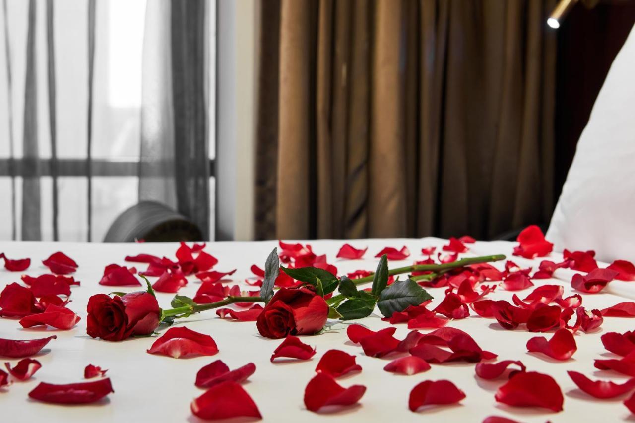 Hotel Stamford Plaza Melburne Exterior foto The photo shows a bed or a table covered with scattered red rose petals. Among the petals, there are a few whole red roses, still with their stems. The background features curtains that appear to be sheer, allowing some light to come through, and the